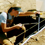 Image of female archaeology student measuring depth of excavation pit