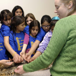 Thumbnail image of a zoology student showing middle school girls from the GAMES program a specimen