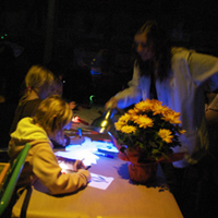 Image of student helping children with glow-in-the-dark crafts