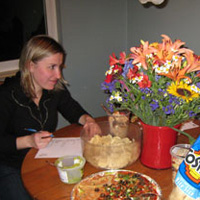 Image of two female Museum Club members at potluck, one filling out a survey form