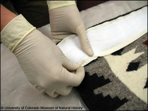 Image of stitching fabric to Navajo rugs for safe hanging