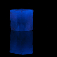 Image of a crystal cube fluorescing blue under UV light
