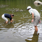 Image of two biology students, one male and one female, wading in a river