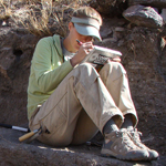 Image of anthropologist in the field writing in a notebook